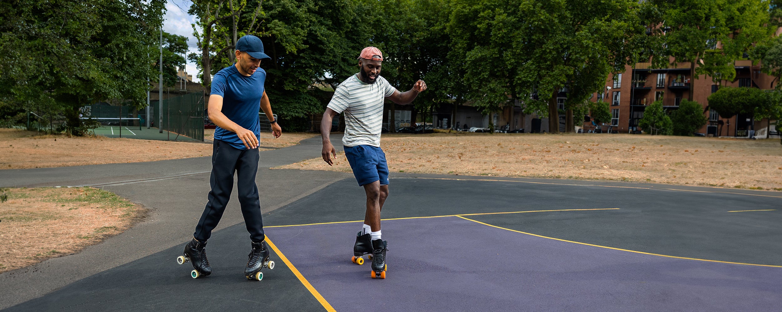 Mellow Moves showing Dean how to do the grapevine on roller skates at Bethnal Green Gardens